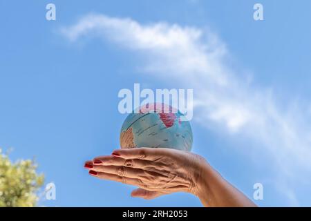 Eine weibliche Hand hält eine Kugel gegen den blauen Himmel Stockfoto