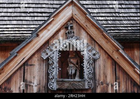 Kompliziertes Fretwork umgibt die Figur Christi mit gefesselten Händen. In Holz geschnitzt auf einem Verandatentor der Holzkirche aus dem späten 1400s. Jahrhundert, Dębno Podhalańskie, Polen. Stockfoto