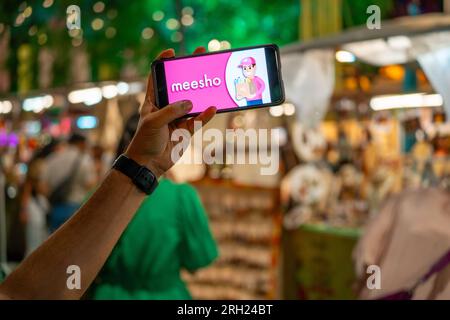 Frau, die ein Handy hält, das das Meesho-Logo des indischen Social Commerce-Startups auf einer Veranstaltung zeigt Stockfoto