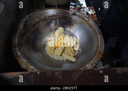 Bereiten Sie in Medan, Indonesien, in einer großen Pfanne mit Eiern indonesische Instantnudeln zu. Straßenessen-Fotografie. Stockfoto