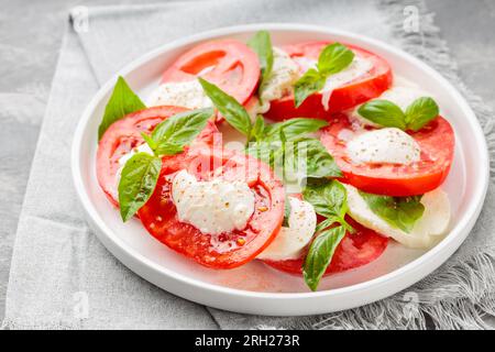 Gourmet-Caprese-Salat auf weißem Teller mit einer Serviette aus grauem Leinen. Schließen Stockfoto