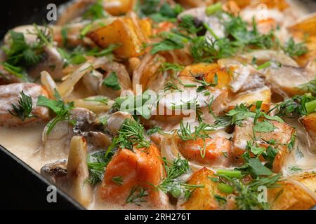 Bratkartoffeln mit Lachs, Pilzen und Gewürzen. Geringe Schärfentiefe Stockfoto