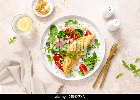 Omelette gefüllt mit Tomaten, Broccoli Feta Käse und frischem grünen Salat. Gesunde Ernährung zum Frühstück. Draufsicht Stockfoto