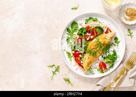 Omelette gefüllt mit Tomaten, Broccoli Feta Käse und frischem grünen Salat. Gesunde Ernährung zum Frühstück. Draufsicht Stockfoto