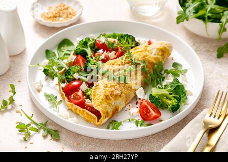 Omelette gefüllt mit Tomaten, Broccoli Feta Käse und frischem grünen Salat. Gesunde Ernährung zum Frühstück Stockfoto