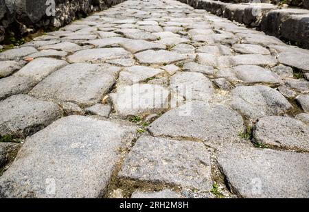 Alte Kopfsteinpflasterstraße in Pompeji, Italien. Graue Granitkopfsteingepflastertextur für den Hintergrund. Felsen der alten römischen Straße. Thema: Bürgersteig, Antiquität Stockfoto