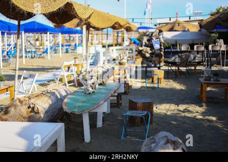 Strandclubkonzept, Essecke oder Café, Restauranttische, strohhaltige natürliche Stühle, Holztische Stockfoto