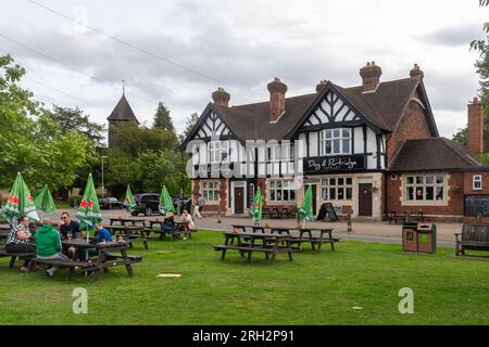 Der Dog & Partridge Pub in Yateley, Hampshire, England, Großbritannien, mit Leuten, die draußen an Tischen sitzen und Drinks auf dem Gras genießen Stockfoto