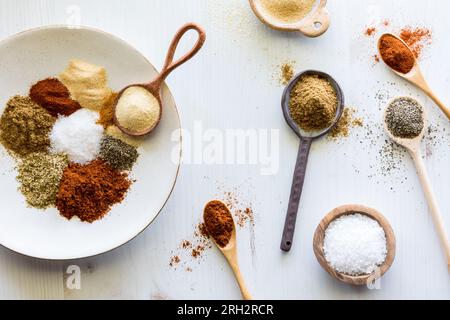 Gewürzhaufen auf verschiedenen Löffeln und ein Teller mit Kopierraum in der Mitte. Stockfoto