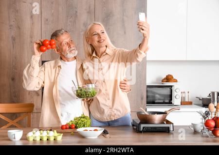 Reifes Paar mit Tomaten, die Selfie in der Küche machen Stockfoto