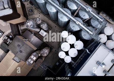 Luftaufnahme direkt über großen Lagertanks in einer Reihe für die Lebensmittelproduktion oder die Lagerung von Chemikalien in einem Industriewerk oder einer Fabrik Stockfoto