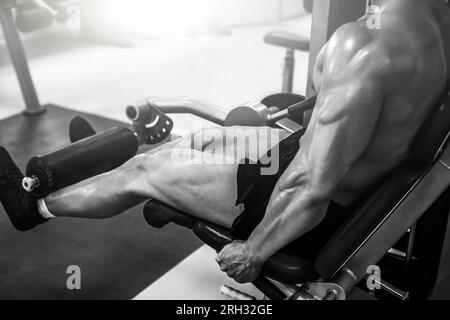 Starker, muskulöser Bodybuilder, der in einem modernen Fitnessstudio Beine mit der Maschine macht, Nahaufnahme Stockfoto