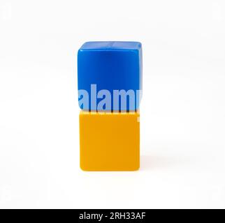 Bunte Kunststoffwürfel für Kinderspiele. Blauer Würfel auf gelbem Würfel. Eins gegen eins. Foto in hoher Qualität. Stockfoto
