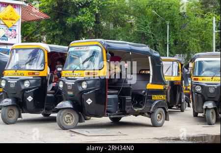 MUMBAI - SEPTEMBER 24: Traditionelle schwarze und gelbe Auto-Rikscha oder Tuk-Tuk, die am 24. September in einer Straße in Mumbai auf Passagiere warten. 2022, Indien Stockfoto