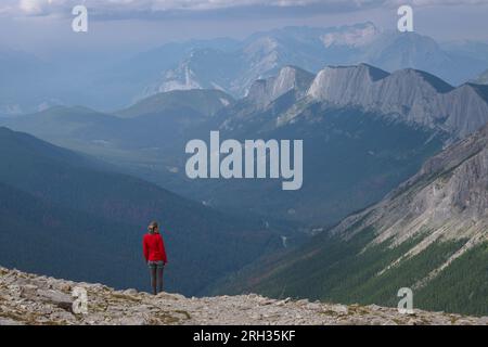 Eine Frau steht am Rande eines Berges und schaut auf das Tal unten in Kanada Stockfoto