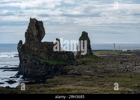 Lavaformationen entlang des Altantischen Ozeans in Londragar, Island, mit dem Malariff Lighthouse im Hintergrund Stockfoto