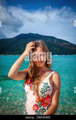 Eine sorgenfreie junge Frau sonnt sich im goldenen Sonnenschein an einem unberührten Strand Stockfoto