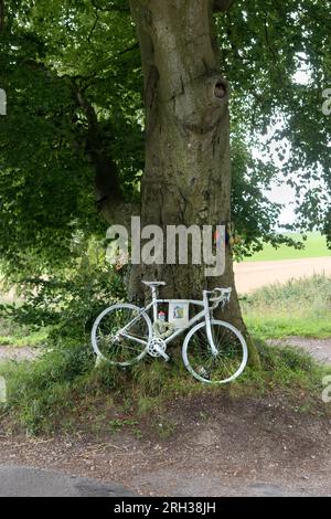 White Memorial Bicycle UK. Ghostcycle auch bekannt als Ghost Bike. Radfahrer auf dem Land, der auf seinem Tretrad getötet wurde, radelte auf einer Landstraße nach Hause. Die Fahrbahnmarkierungen waren kaum sichtbar. Sarum Road und Woodman Lane, bei Sparsholt. Hampshire UK 2023 2020s England. HOMER SYKES Stockfoto