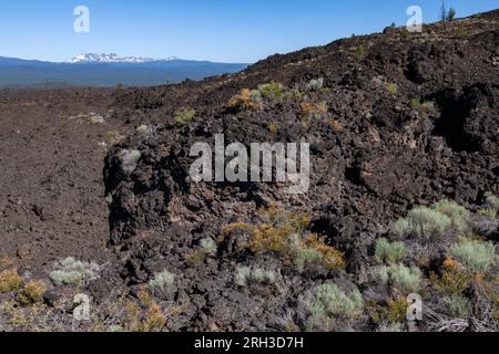 Das Lavafeld am Newberry Volcanic National Monument erstreckt sich westlich in Richtung der Vulkane South Sister, Broken Top und North Sister in der Deschutes Nationa Stockfoto