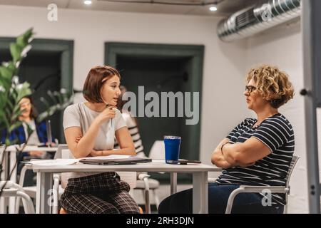 Zwei Kollegen, die während der Arbeit miteinander sprechen und Ideen austauschen Stockfoto