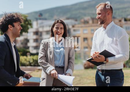Junge Mitarbeiter, die in der Stadt in einer guten Atmosphäre arbeiten. Sie diskutieren über Arbeit, Planung, Witze und Lachen. Positives Energiekonzept Stockfoto