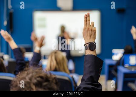 Ein Foto von Schülern, die während des Vortrags in der Schule die Hand heben und Fragen stellen Stockfoto