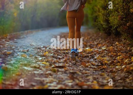 Hallo Herbst. Nahaufnahme einer fit-Frau mittleren Alters in Fitnesskleidung beim Joggen im Park. Stockfoto