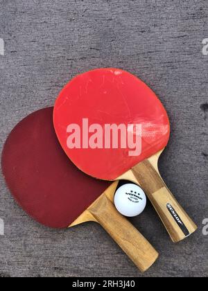 Zwei Tischtennisschläger oder Tischtennisschläger und Bälle Ein blauer Tisch Stockfoto