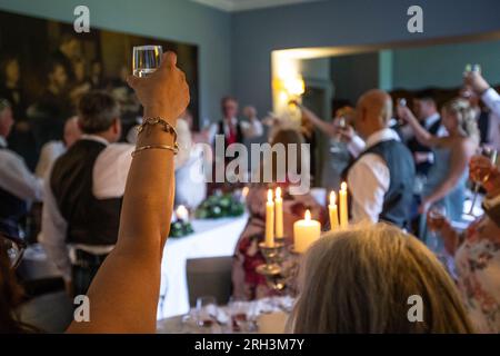 Hochzeitsgäste heben die Gläser und toasten während der Hochzeitsfrühstücksreden. Stockfoto