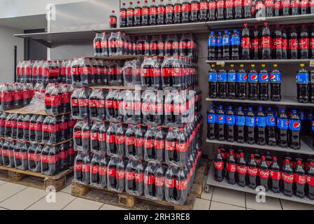 Italien – 08. August 2023: Coca-Cola in Kunststoffflaschen, verpackt in Kunststofffolie und gestapelt auf Paletten und Pespi-Flasche im Regal für den Verkauf in italienischem Stor Stockfoto