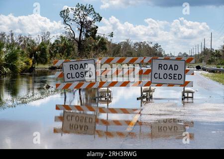 Die Straße in Florida wurde nach Hurrikanregen überflutet, und die Straße wurde durch Schilder gesperrt, die das Fahren von Autos blockieren. Sicherheit des Transports bei Naturkatastrophen Stockfoto