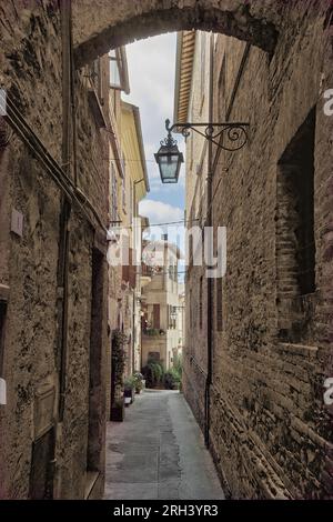 Bevagna, Umbrien, Italien. Eine Gasse, gesäumt von alten Häusern mit Stein- und Ziegelwänden in der mittelalterlichen Altstadt. Stockfoto