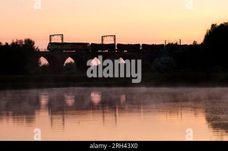 Colas Rail Freight Lokomotive der Baureihe 70 70811 überquert das Garnock Longford-Viadukt südlich von Kilwinning und beförderte einen Güterzug mit Tanksat-Sonnenuntergang Stockfoto