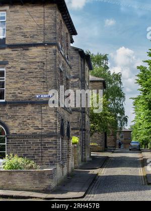 Die Ecke William Henry Street und Albert Terrace in Saltaire, Yorkshire, mit Kopfsteinpflaster, zeigt die Hütten der Mühlenarbeiter aus der nahegelegenen Salze Mill. Stockfoto