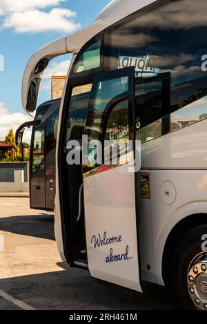 Salisbury, Wiltshire, England, Großbritannien. 6. August 2023. Kommerzielle Reisebusse, die im Stadtzentrum geparkt sind, eine offene Tür mit Nachricht, willkommen an Bord. Stockfoto