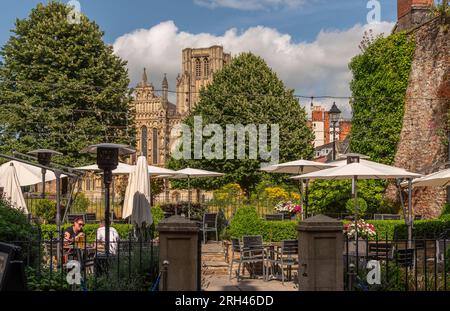 Wells, Somerset, England, Großbritannien. 21. Juni 2023 Speisesaal im Hotelgarten mit Gästen, die einen Drink mit Blick auf die Kathedrale von Wells genießen, Stockfoto