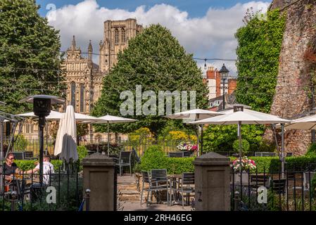 Wells, Somerset, England, Großbritannien. 21. Juni 2023 Speisesaal im Hotelgarten mit Gästen, die einen Drink mit Blick auf die Kathedrale von Wells genießen, Stockfoto