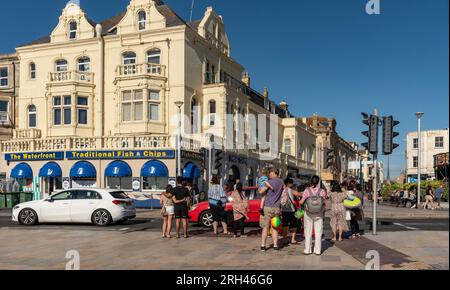 Weston Super Mare, Somerset, England, Großbritannien. 25. Juni 2023 Urlauber überqueren die Straße am Strand in Richtung Stadtzentrum, Weston. Stockfoto