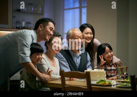 Eine asiatische Familie aus drei Generationen zu Hause, um den Hochzeitstag des Seniorenpaares zu feiern Stockfoto