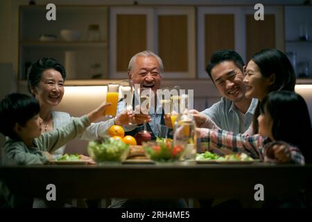 Eine asiatische Familie aus drei Generationen zu Hause, die den Urlaub mit einem Toast feiert Stockfoto