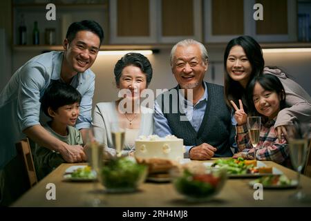 Eine asiatische Familie aus drei Generationen zu Hause, um den Hochzeitstag des Seniorenpaares zu feiern Stockfoto