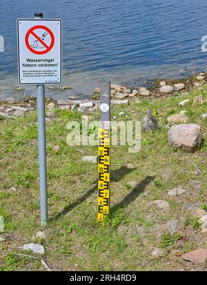 Strausberg, Deutschland. 11. Aug. 2023. Eine Wasserstandsanzeige am Straussee ist seit langem trocken. Der See hat etwa zehn Jahre lang die Hälfte seines Wassers verloren. Seit 2014 ist der Wasserstand jedes Jahr um etwa 20 Zentimeter gesunken. Die Ursache für den Wasserverlust ist nicht bekannt. Zu diesem Thema wurde ein Sachverständigengutachten in Auftrag gegeben. Kredit: Patrick Pleul/dpa/Alamy Live News Stockfoto