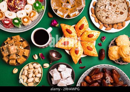 Nahöstliche Süßigkeiten, türkische Köstlichkeiten und schwarzer Kaffee auf grünem Hintergrund. Arabisches Dessertsortiment, rahat lokum, Halva, Sherber, Pismaniye mit Nuss Stockfoto