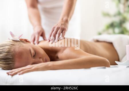 Eine wunderschöne Frau genießt eine entspannende Rückenmassage im kosmetischen Wellnesscenter. Stockfoto