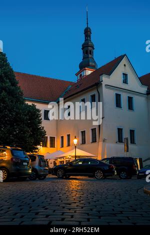 Enge Kopfsteinpflasterstraße, typisches Gebäude und Turm am Abend im Hintergrund in der Altstadt von Prag, Tschechische Republik. Stockfoto