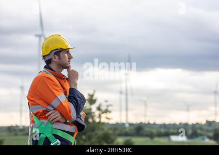Professioneller Ingenieur, männlicher Arbeiter, der beim Windturbinenbetrieb am Kinn denkt Stockfoto