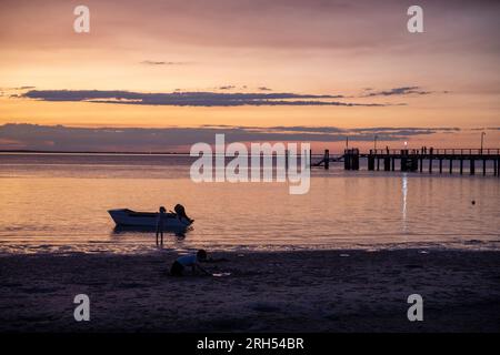 Fraser Island K'gari Sonnenuntergang über kingfisher Bay und Coral Sea mit Silhouetten Boot, Person und Fähre Pier, Queensland, Australien Stockfoto