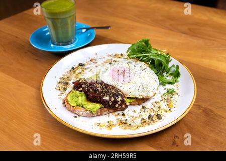 Zerkleinerte Avocado auf Sauerteigbrot mit Ei, Chutney und Dukkah im Stables Cafe bei Orleans House Gallery, Twickenham, London, England Stockfoto