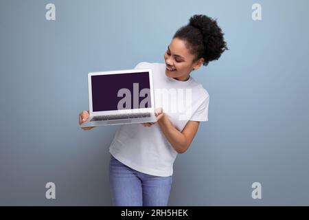 Junge brünette latina im weißen T-Shirt, die per Fernzugriff mit einem Laptop lernt Stockfoto