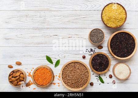 Verschiedene Superfoods in der kleinen Schüssel auf farbigem Hintergrund. Superfood wie Reis, Chia, Quinoa, Linsen, Nüsse, Sesamsamen, Mandeln. Kopierbereich der Draufsicht. Stockfoto